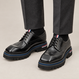 Black Wingtip Derby Shoes with Metal Eyelets — on-foot studio view